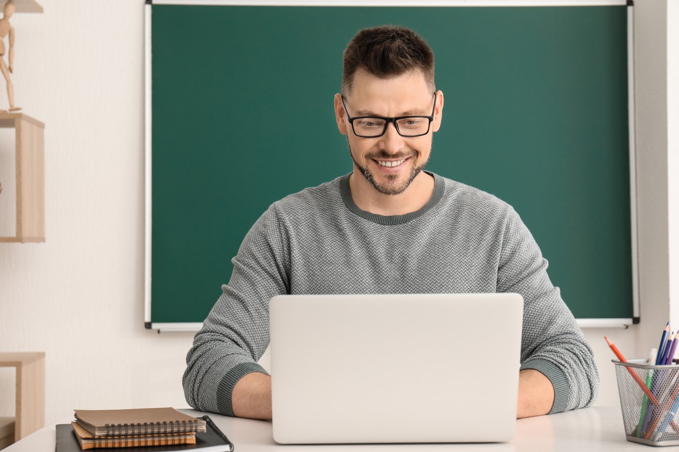 Handsome Male Teacher with Laptop in Classroom